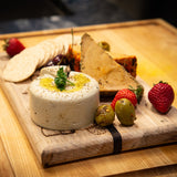 Blocks of vegan cheese on a cutting board with accoutrements 