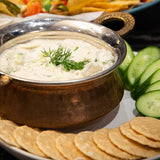 A bowl of vegan tzatziki with crackers and cucumber
